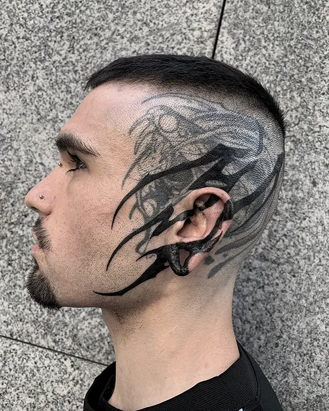 Tatuaje blastover de estilo abstracto tekno tribal hechosobre una serpiente, extendido por la sien, la oreja y parte de la cara, hecho por Moi Tattoo en Karratu Tattoo Estudio de Tatuajes.