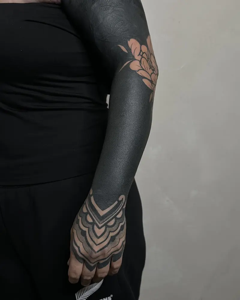 tatuaje negro blackout relleno solido en un brazo, terminado en un ornamental en la mano. hecho por javi tikka tatuador en karratu tattoo bilbao