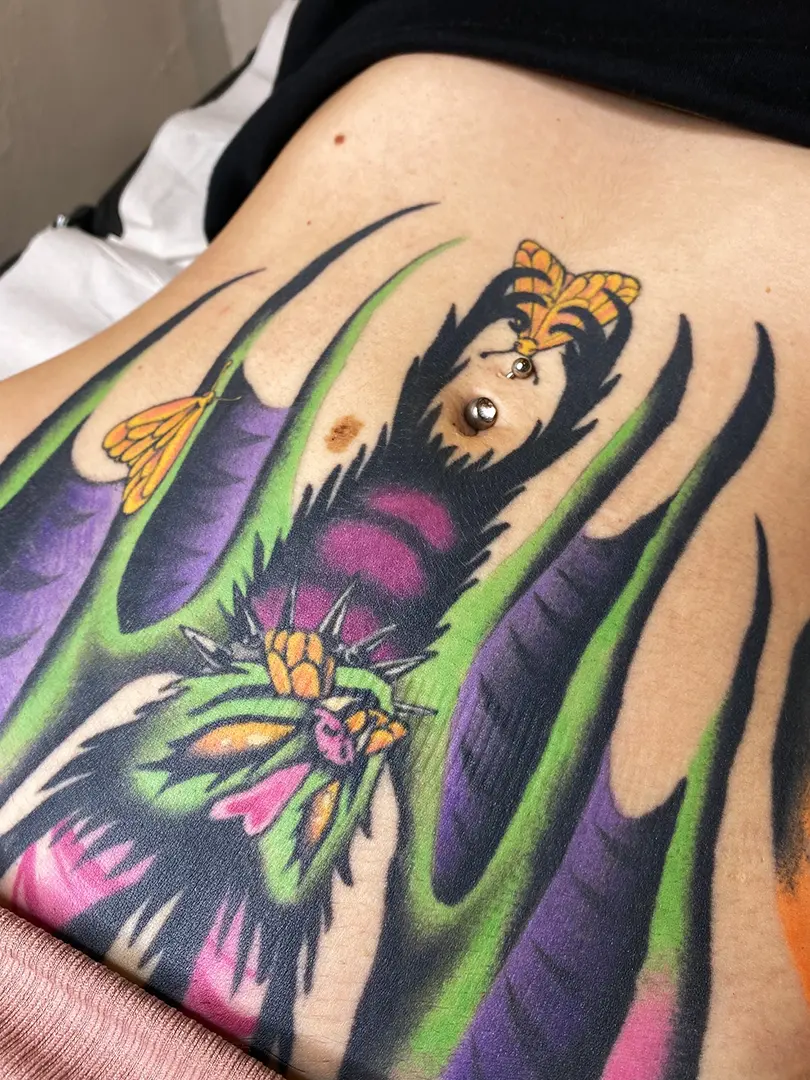 Tatuaje realizado a color por Don Ander de organos, en Bilbao. El tattoo representa a un murciélago que coge unas mariposas con las patas, en estilo ilustración sin líneas, con colores morados, rosas, verdes y amarillos