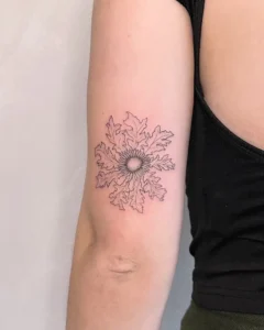 Detalle de tatuaje de línea fina de un eguzkilore (flor de protección vasca), realizado en el brazo en Karratu Tattoo, Bilbao