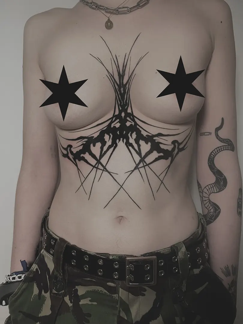 Tatuaje neotribal con espinas en la zona del underboob y el esternón con técnica blackwork, diseñado por Marta Tanta.