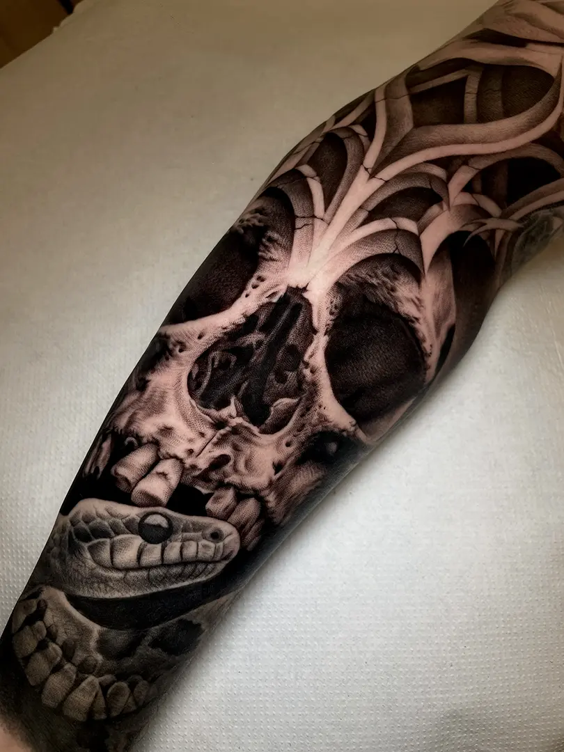 Tatuaje realista de una calavera con una serpiente en blanco y negro, pieza detallada de Helena Ayala.