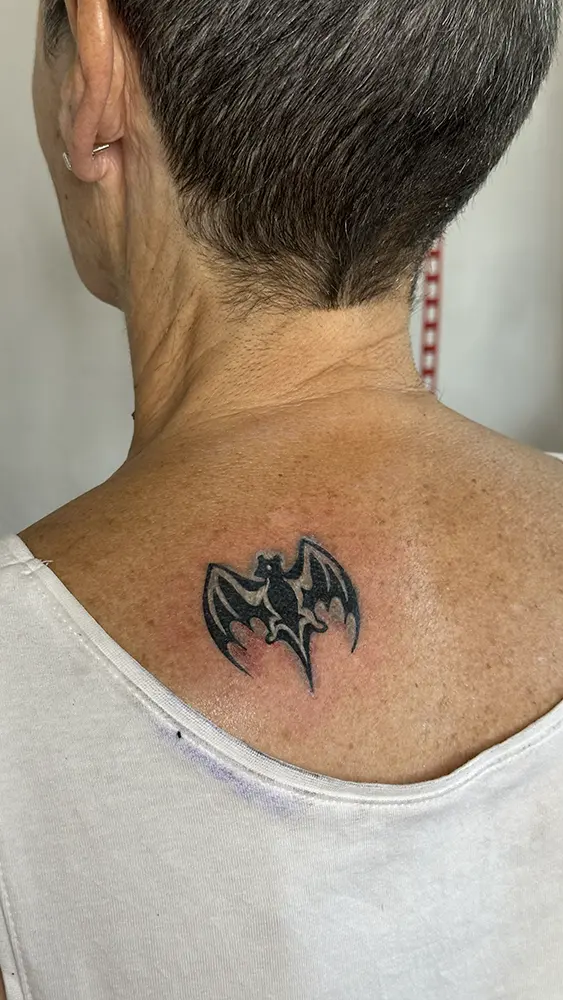 Tatuaje de murciélago de Bacardi restaurado con tinta blanca y con tinta negra nueva redefiniendo las formas.