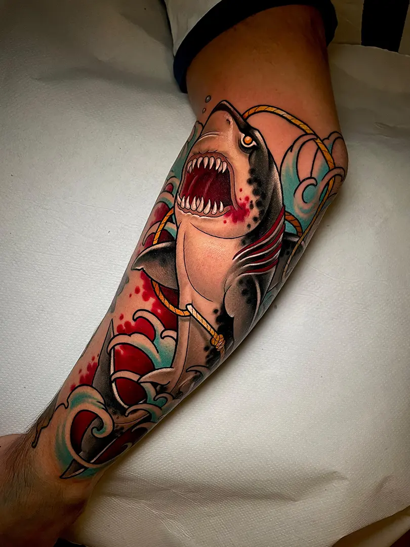 Tatuaje de un tiburón de estilo tradicional / neotradicional con olas japonesas alrededor, sangre y sogas. Hecho a color (rojos, azules y grises) por Helena Ayala