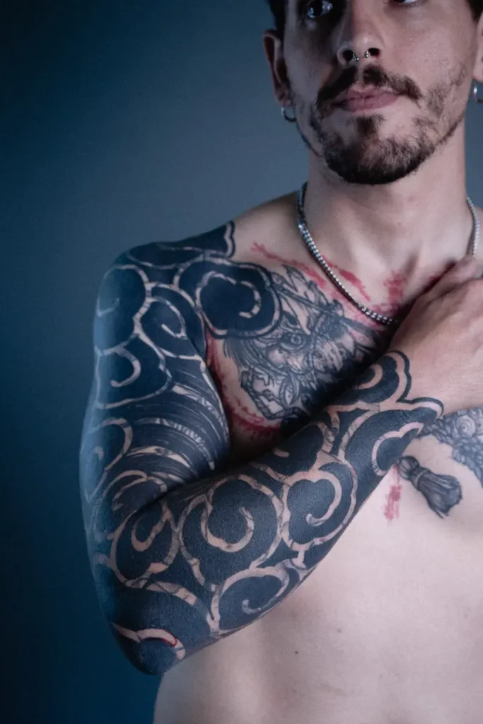 Tatuaje Blastover hecho por Javi Tikka, con motivos japoneses realizados con negro plano tipo blackout en todo el brazo