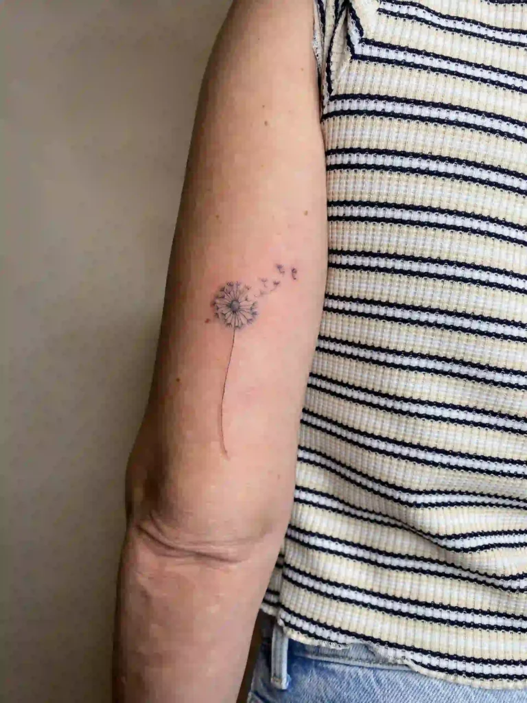 Tatuaje de línea fina (fine line) de un diente de león realizado por Karratu Tattoo Bilbao, ideal como recuerdo minimalista en el brazo.